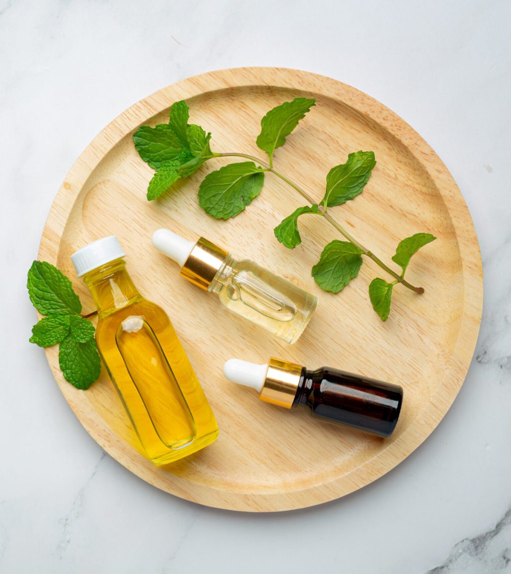 Essential oil of peppermint in bottle with fresh green peppermint